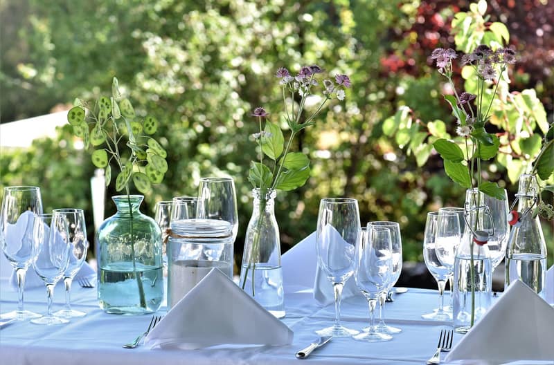 A long garden table set with glasses, napkins and flowers